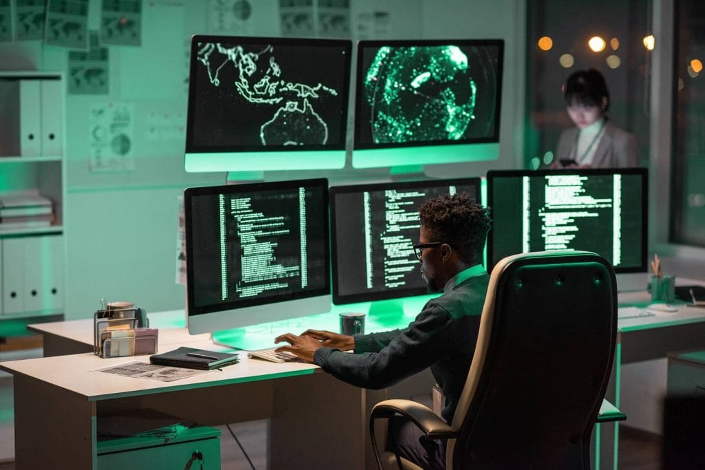 Fotografie stoc: specialist în securitate cibernetică analizând date pe mai multe monitoare
